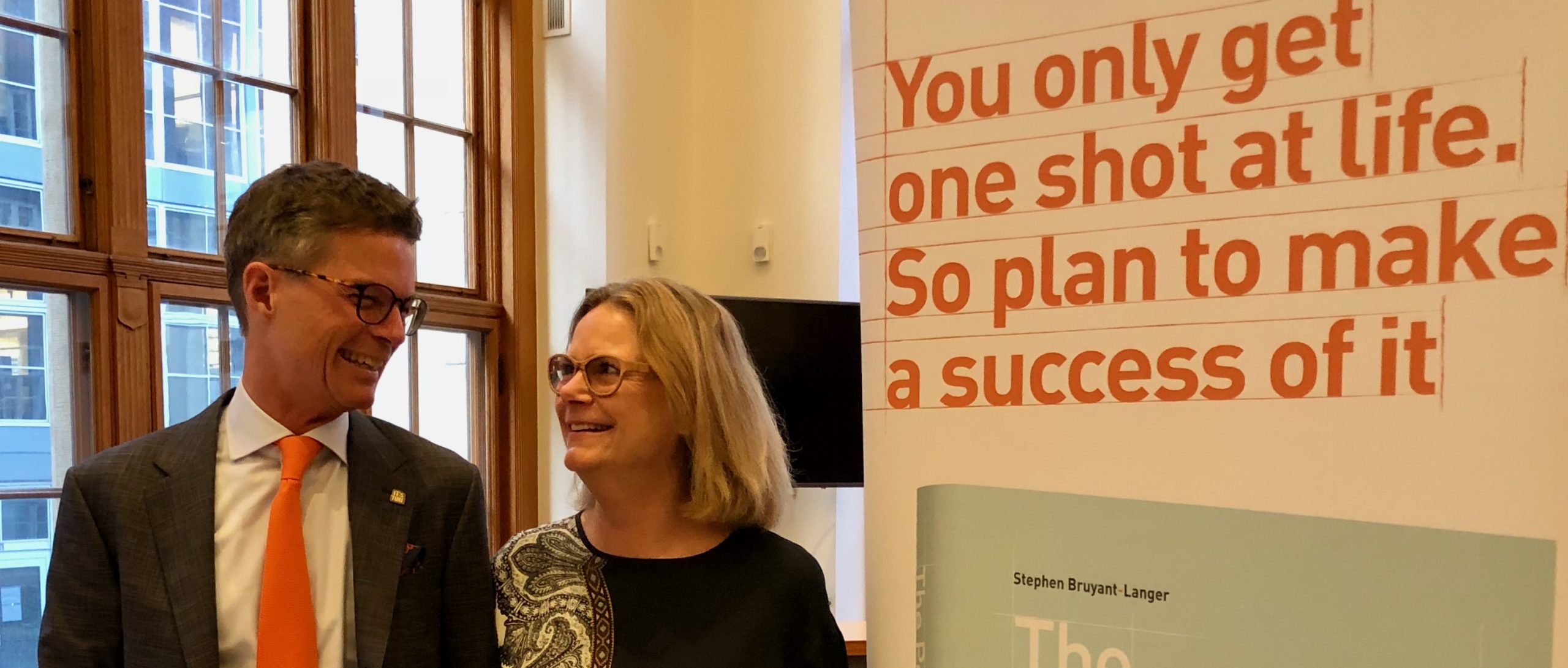 Portrait of Mette and Stephen Bruyant-Langer with book roll-up